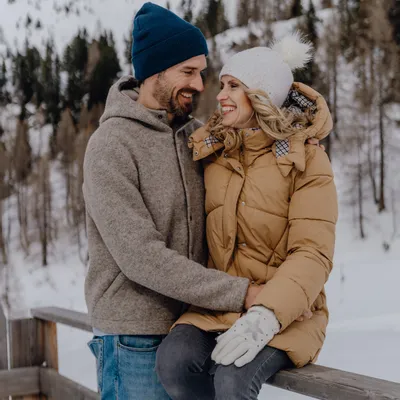 Smiling couple in winter clothing with snowy mountain background